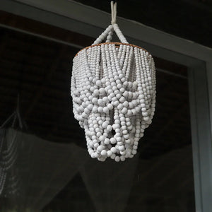 Handmade Balinese white seashell chandelier hanging in front of a window