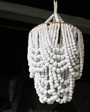 Handmade white wood bead chandelier in boho Balinese style, hanging indoors