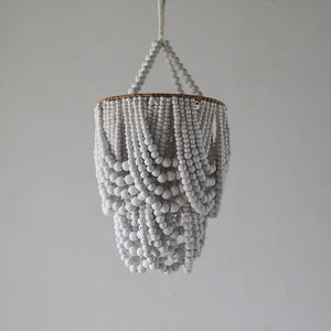 Handmade white wooden bead chandelier with cascading design on neutral background