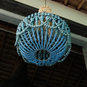 Handcrafted blue beaded chandelier with natural accents, hanging under a wooden ceiling