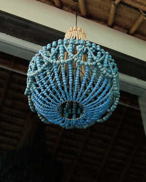 Handcrafted blue beaded chandelier with natural accents, hanging under a wooden ceiling