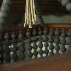 Close-up of a handmade wooden beaded chandelier with rope tassel, Balinese decor detail