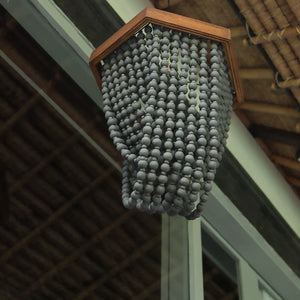Handcrafted gray bead chandelier with hexagonal wood frame hanging from a ceiling