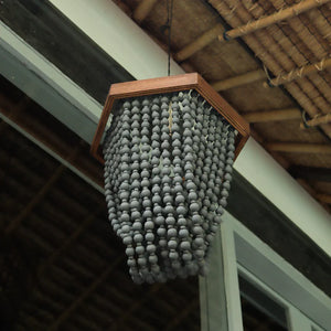 Hexagonal boho chandelier with dark beads hanging from a natural bamboo ceiling