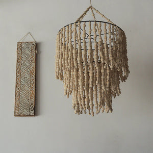 Handmade wooden bead chandelier and carved wall art on neutral wall