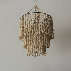 Handmade wooden beaded chandelier with natural finish hanging against a light wall.