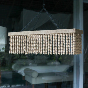 Rectangular natural wood bead chandelier with jute accents, hanging indoors by window