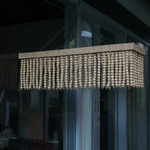 Rectangular beaded wood chandelier with natural finish, hanging indoors near glass doors