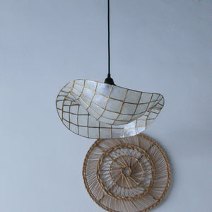 Handcrafted seashell pendant light with gold grid, paired with woven rattan wall decor for boho coastal style