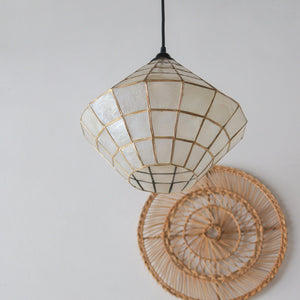 Handcrafted mother-of-pearl pendant light with gold grid, paired with woven rattan wall decor