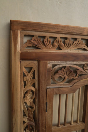 Hand-carved Balinese wooden door with intricate floral and leaf patterns