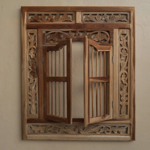 Hand-carved Balinese wooden window with intricate floral patterns on beige wall