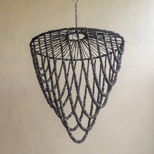 Handmade dark wood bead chandelier with layered draping design against neutral wall