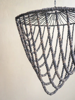 Handmade black beaded chandelier with cascading strings against a neutral wall