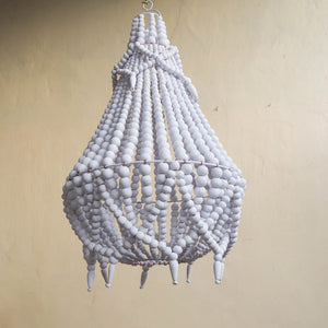 Handmade white beaded chandelier with boho coastal style against a beige wall