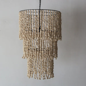 Handmade Balinese seashell chandelier with layered natural beads against a plain wall