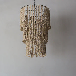 Handmade natural bead chandelier with cascading strands against a plain wall