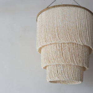 Handmade Balinese seashell chandelier with layered neutral beaded design, hanging on chain