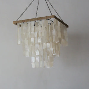 Handmade rectangular seashell chandelier with cascading natural shell pieces on white wall