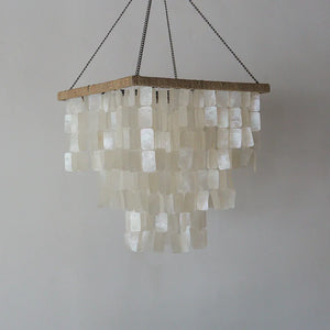 Handmade seashell chandelier with layered rectangular shell pieces and a natural wood frame.
