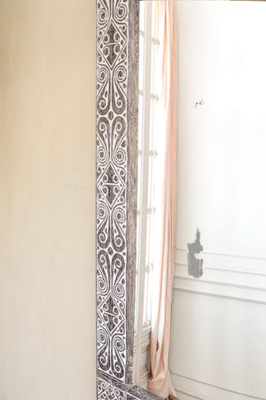 Hand-carved wooden mirror with intricate Balinese patterns in a bright room