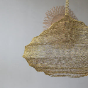 Handmade gold wire pendant light in boho style with a sunburst decor accent in the background