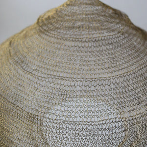 Close-up of handmade woven wire pendant lampshade with intricate gold pattern
