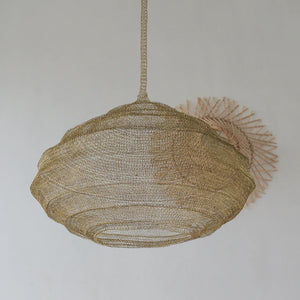 Handwoven rattan pendant light with natural finish, hanging against a white wall