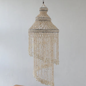 Handmade Balinese seashell chandelier with layered spiral design against white wall