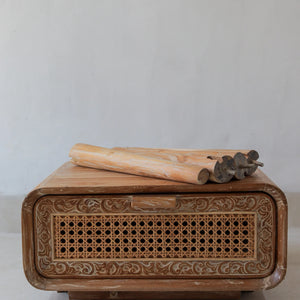 Hand-carved wood table with intricate rattan front panel and tools on top