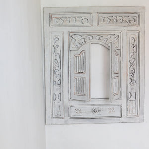 Hand-carved whitewashed Balinese wooden window frame with intricate floral patterns