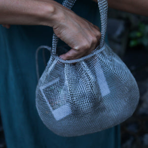 Wire Mesh Hand Woven Bag Lily held by a person, showcasing its unique handwoven brass mesh texture.
