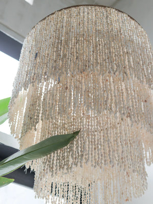 Handmade seashell chandelier with cascading beads in natural light, tropical decor accent