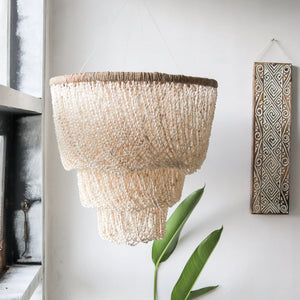 Handmade Balinese seashell chandelier hanging in a modern, minimalist room