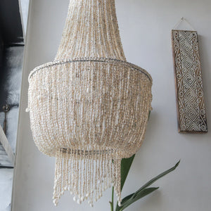 Handmade seashell chandelier with cascading beads, Balinese decor in modern interior.