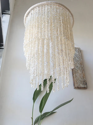 Handmade Balinese seashell chandelier with hanging shell strands in a bright modern room