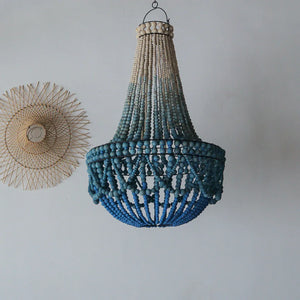 Handmade blue beaded chandelier and woven wall decor on light wall, Balinese style