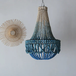 Blue beaded seashell chandelier with natural rattan wall decor on white background