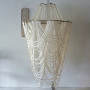 Large handmade seashell chandelier with cascading shell strands in minimalist room