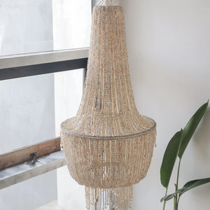 Handmade seashell chandelier with cascading beads in a modern interior by a window