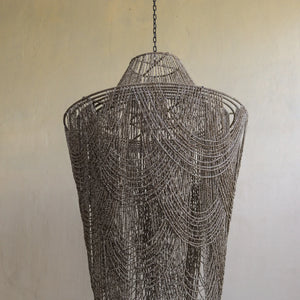 Large beige beaded pendant light with intricate handcrafted design, hanging from a chain