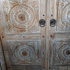 Hand-carved wooden door with floral Balinese patterns and antique metal handles