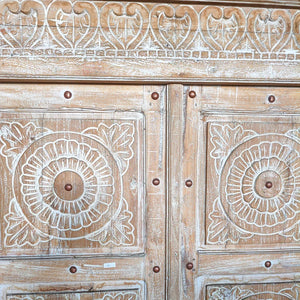 Hand-carved Balinese wooden door with floral and heart patterns, rustic finish