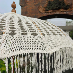Handmade macrame boho umbrella with cotton fringe and wooden finial, outdoor setting
