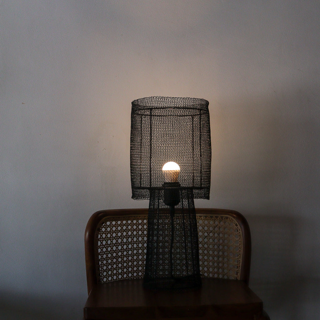 Wire mesh lamp on a chair against a plain wall