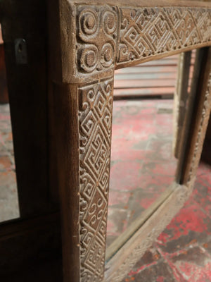 Hand-carved wooden mirror frame with intricate tribal patterns and rustic finish