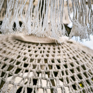 Close-up of off-white macrame Balinese umbrella with woven texture and fringe details