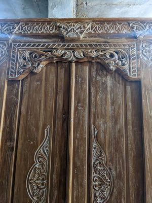 Hand-carved Balinese wooden door with intricate floral motifs and natural wood finish
