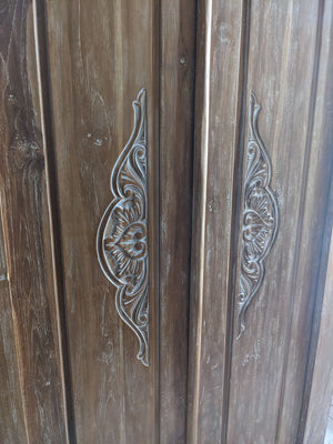 Hand-carved wooden Bali door with intricate floral patterns and natural wood finish
