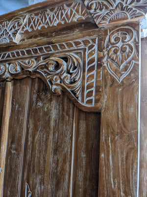 Balinese hand-carved wooden door with intricate patterns and rustic finish